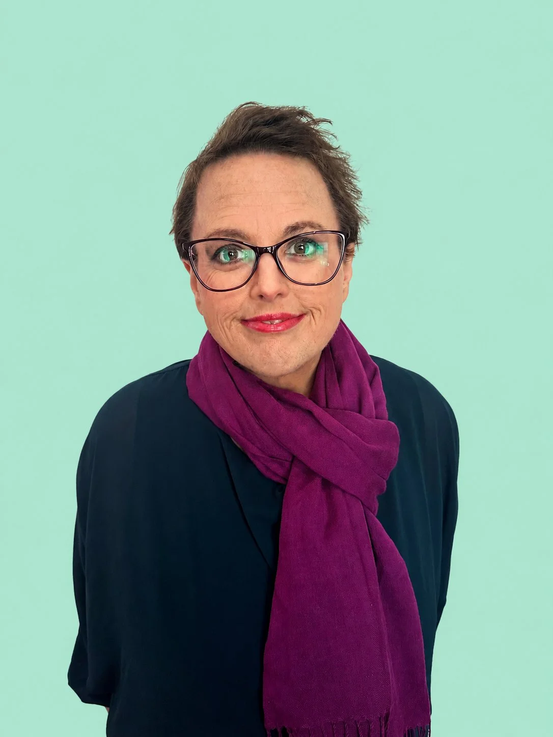 Janelle Baird, founder of Matriarch Advisory, smiling at the camera against a mint background