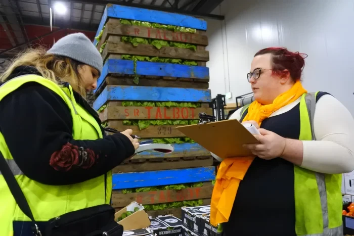 Janelle with a clipboard beside produce crates at the wholesale market